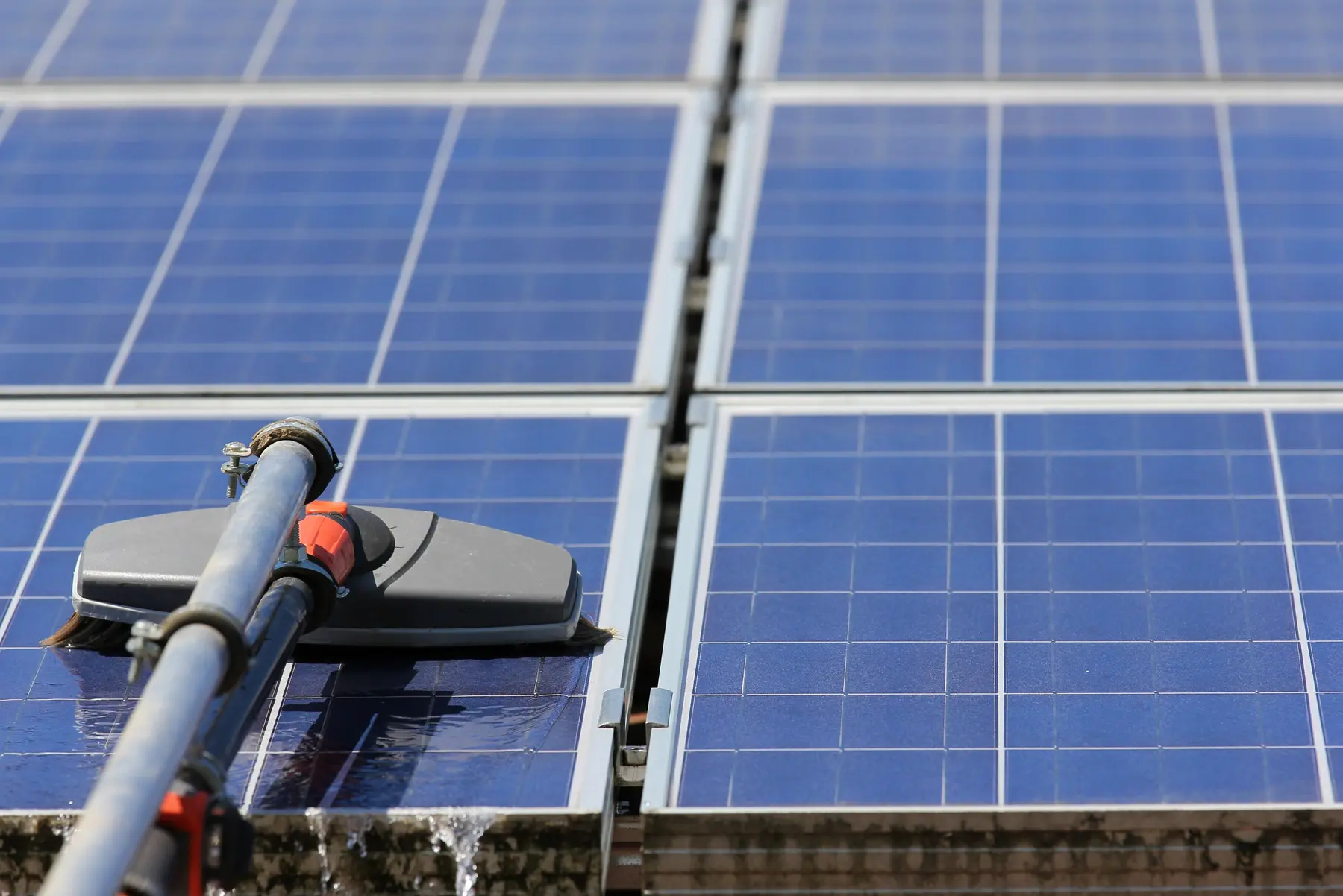 Cabezal de cepillo con agua abundante escurriendo entre dos placas solares